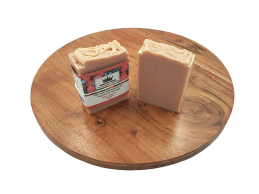 Two bars of soap on a wooden round tray with a white background