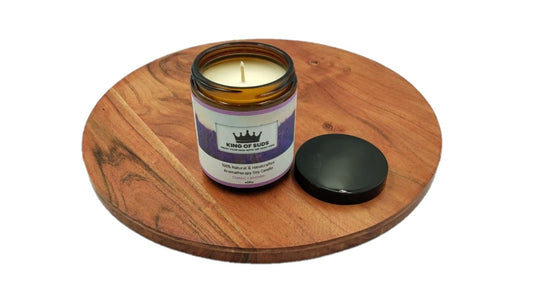 Candle in an amber glass jar on a wooden coaster with a white background