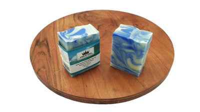Two bars of blue and white soap with a box on a wooden surface