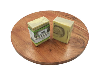 Two bars of soap on a wooden round board with a white background