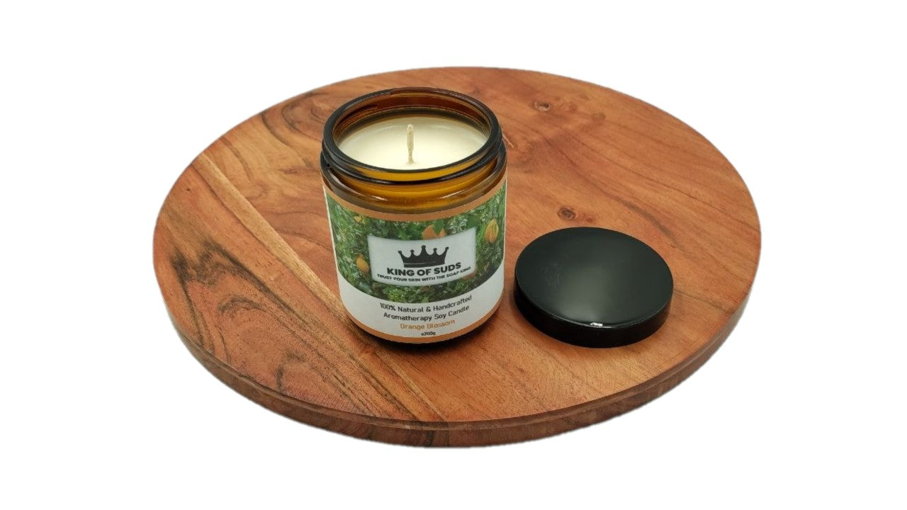 Candle in an amber glass jar on a wooden coaster with a white background