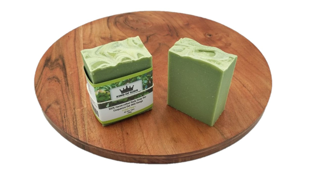 Two green bars of soap on a wooden surface with a visible brand label.