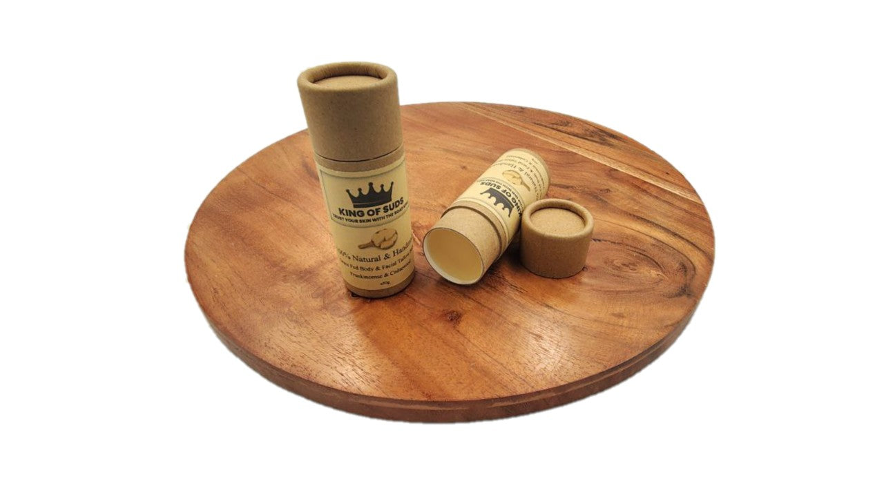 Two cardboard tubes balms with branding on a wooden surface