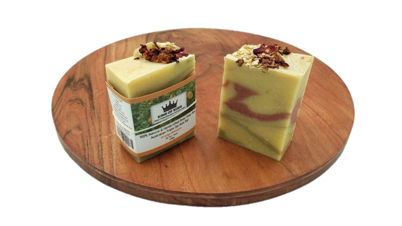 Two bars of soap on a wooden tray with a white background